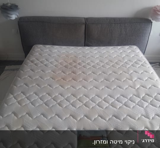 מזרן עם כתם גדול על רקע מיטה אפורה